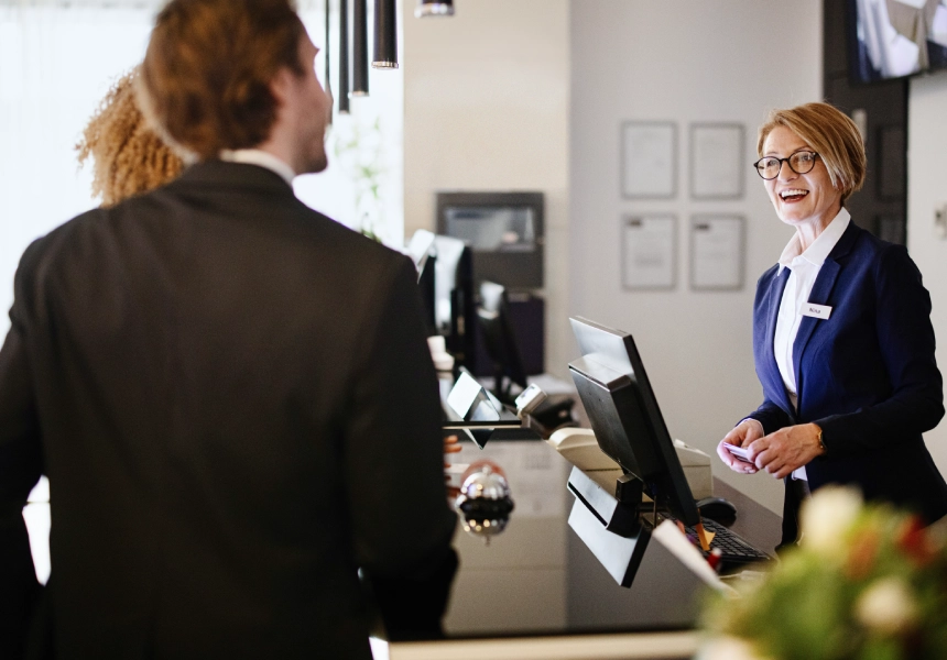 Happy receptionist assisting hotel guests.