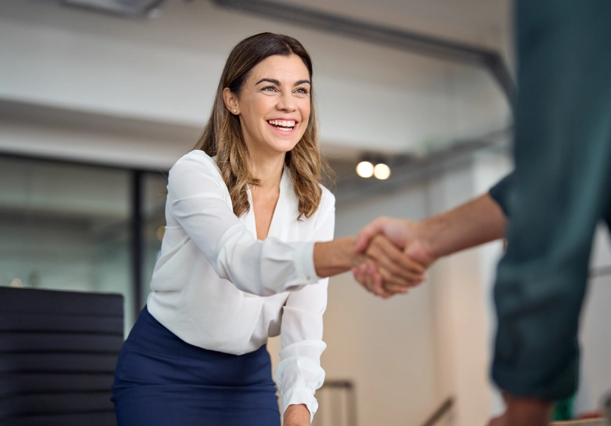 Smiling businesswoman shaking hands in office.